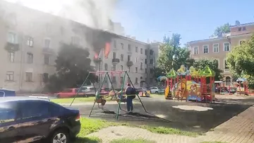 Детишки в Санкт-Петербурге, катаясь на качелях, наблюдали за огнем, вырывающимся из окон заброшенного здания