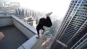 Парень тренируется на краю крыши небоскреба