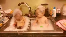 Два очаровательных близнеца веселятся в “ванной”.