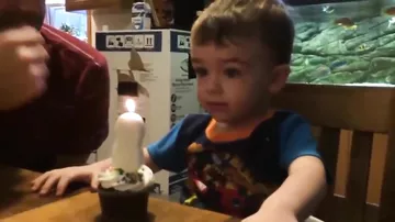 Папа помог своему сыну задуть свечу на торте